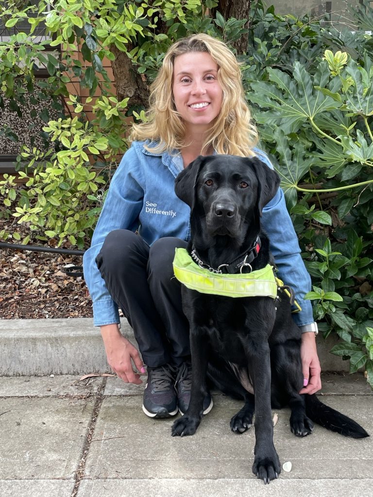 female sitting behind a black labrador